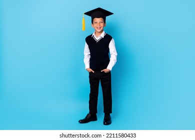 Full size photo of cheerful positive boy put hands pockets wear mortarboard isolated on blue color background - Powered by Shutterstock