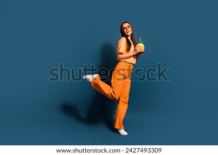 Full size photo of cheerful woman dressed yellow t-shirt dancing hold cocktail at summer party isolated on dark blue color background