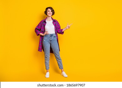 Full size photo of cheerful young lady point empty space suggest decision wear plaid shirt isolated on yellow color background - Powered by Shutterstock