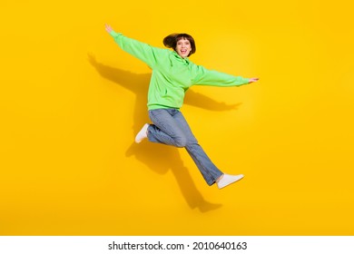 Full size photo of cheerful young happy cute woman jump up good doom hands wings isolated on yellow color background