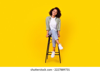 Full size photo of cheery young woman curly hair sit chair have rest chatting wear trendy khaki outfit isolated on yellow color background - Shutterstock ID 2227889731