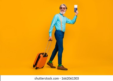 Full Size Photo Of Cool Grandpa Hold Tickets Rolling Suitcase Walk Registration Table Raise Passport Wear Blue Shirt Suspenders Bow Tie Pants Boots Socks Isolated Yellow Color Background