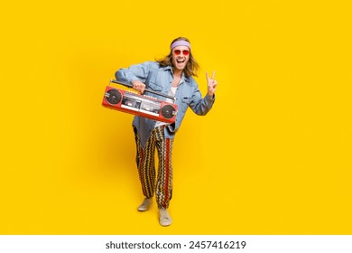 Full size photo of cool young man boombox show v-sign empty space wear denim shirt isolated on yellow color background - Powered by Shutterstock