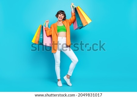 Full size photo of cool young brunette lady hold bags wear blazer top jeans shoes isolated on teal background