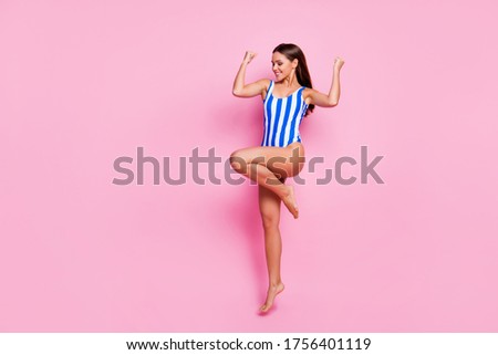 Full size photo of crazy astonished lady fit legs long straight hairdo jump rejoicing showing nice arms muscles wear striped bodysuit isolated pastel pink color background