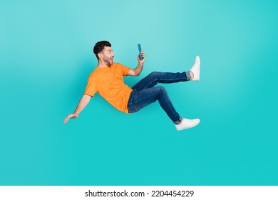 Full size photo of crazy blogger guy fall downward read network news isolated on cyan color background - Shutterstock ID 2204454229