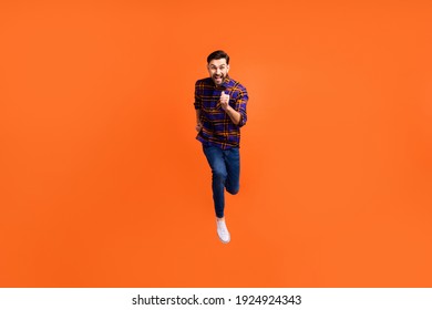 Full size photo of crazy cheerful man jumping running toothy smile isolated on orange color background - Shutterstock ID 1924924343