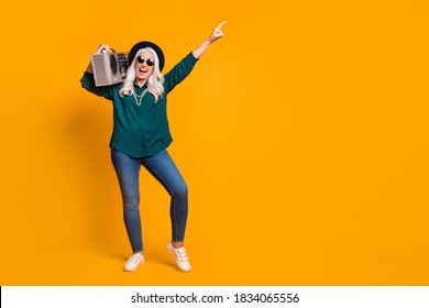 Full Size Photo Of Crazy Granny Lady Senior Party Chill Hold Tape Recorder On Shoulder Direct Finger Up Wear Green Shirt Sun Specs Necklace Retro Cap Shoes Isolated Yellow Color Background