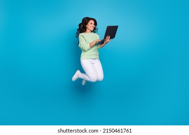 Full Size Photo Of Cute Mature Brunette Lady Jump Hold Laptop Wear Shirt Pants Shoes Isolated On Blue Background