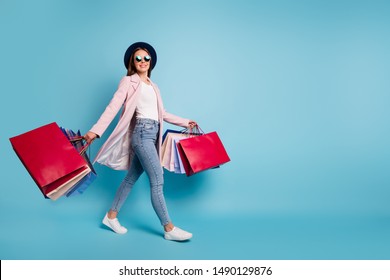 Full size photo of cute pretty cheerful lady in eyeglasses eyewear go shopping for bargains wear season cote denim jeans isolated over blue background - Powered by Shutterstock