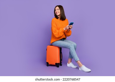 Full size photo of cute young woman hold device wait taxi service wear trendy orange knitwear garment isolated on violet color background - Shutterstock ID 2220768547