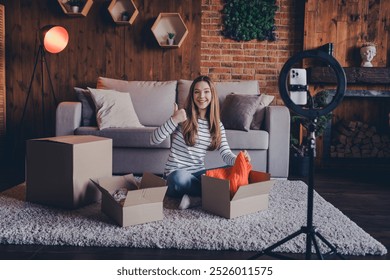 Full size photo of cute young girl thumb up unpack shipment tripod holder smart phone record video modern loft interior apartment indoors - Powered by Shutterstock