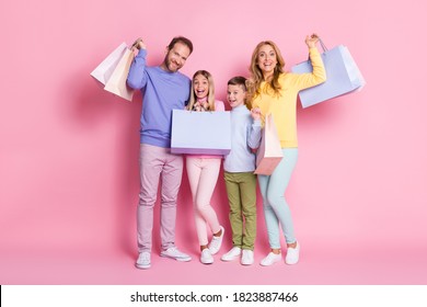 Full Size Photo Of Dream Amazed Family Daddy Mommy Holding Shopping Bags Isolated Over Pink Pastel Color Background