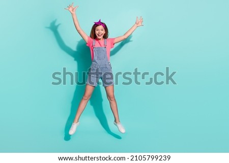 Full size photo of excited preteen kid jump raise hands up wear t-shirt isolated over cyan color background