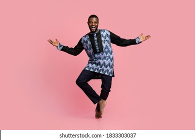 Full size photo of friendly black man dancing over pink studio background, copy space. Cheerful african american guy wearing traditional costume and showing welcoming gesture, studio shot - Powered by Shutterstock