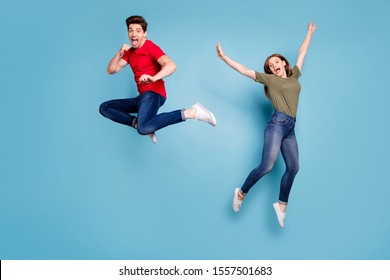 Full size photo of funky crazy two people spouses students man fight kick hands fists woman jump fool raise arms wear green red t-shirt denim jeans sneakers isolated blue color background