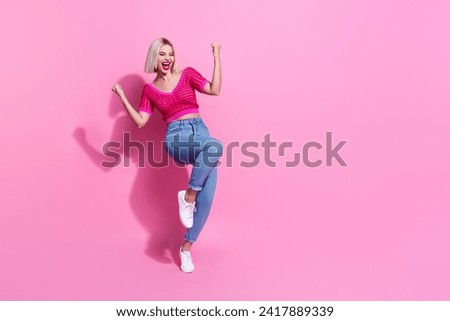 Full size photo of funky optimistic woman dressed knit top denim pants screaming raising fists win gambling isolated on pink background