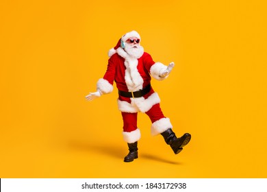 Full size photo of funky santa claus with grey beard listen magic x-mas christmas music headset dance party wear cap headwear sunglass isolated bright shine color background