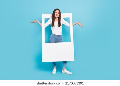 Full Size Photo Of Funny Girl With White Frame Shrug Shoulders Not Happy With Photoshoot Isolated On Blue Color Background