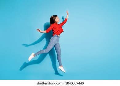 Full size photo of funny lady jump up good mood wear knitted red pullover sneakers jeans isolated blue color background - Shutterstock ID 1840889440