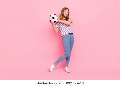 Full size photo of funny teen blond girl hold ball wear t-shirt jeans shoes isolated on pink color background