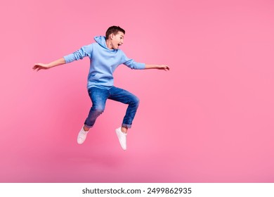 Full size photo of funny teenager boy surfing empty space wear trendy blue outfit isolated on pink color background - Powered by Shutterstock