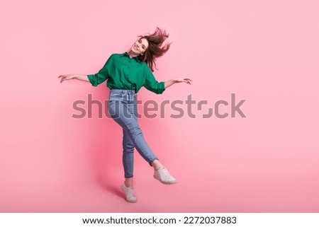 Full size photo of good mood cheerful nice pretty girl wear jeans green shirt white sneakers dancing on toes isolated on pink background