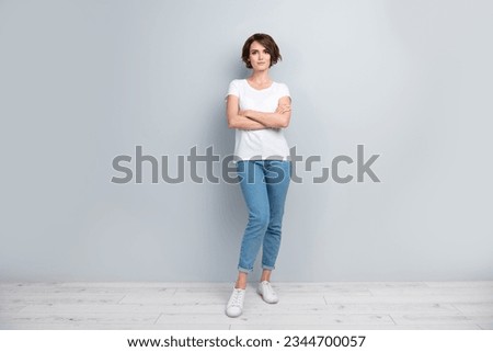 Full size photo of good mood adorable woman dressed white t-shirt denim trousers holding arms folded isolated on gray color background