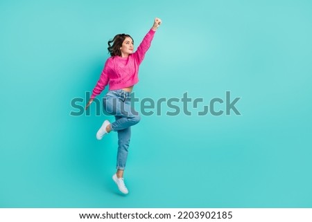 Full size photo of gorgeous powerful woman wavy hairstyle pink pullover jeans raise arm empty space isolated on teal color background