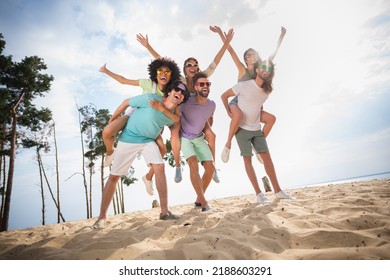 Full size photo of group overjoyed carefree people piggyback rejoice walk sand beach free time outside - Powered by Shutterstock