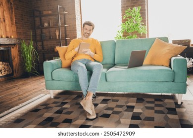 Full size photo of handsome mature man sit couch online study write notebook dressed yellow outfit cozy day light home interior living room