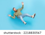 Full size photo of handsome young man frightened falling down slipping dressed stylish khaki outfit isolated on aquamarine color background