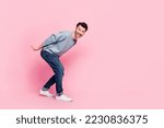 Full size photo of handsome young guy carry heavy invisible box empty space dressed trendy blue outfit isolated on pink color background