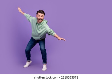 Full size photo of handsome young man spread hands surfing have fun dressed stylish khaki clothes isolated on purple color background - Powered by Shutterstock