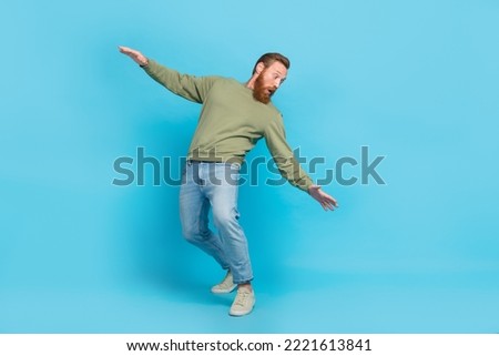 Full size photo of handsome young man bending look back avoid falling dressed stylish khaki outfit isolated on aquamarine color background