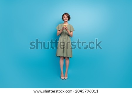 Full size photo of happy charming young woman hold phone like comment write isolated on blue color background