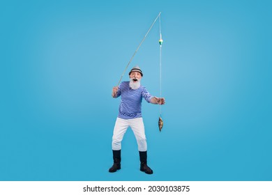 Full size photo of happy cool positive amazed old man hold hand fishing rod catch isolated on blue color background - Shutterstock ID 2030103875