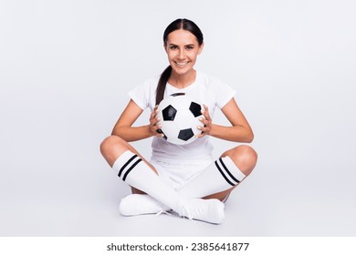 Full size photo of happy positive young woman hold ball hands sit floor isolated on grey color background - Powered by Shutterstock