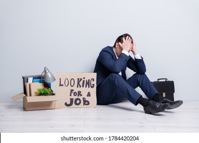 Full size photo of loser mature guy jobless business man handmade placard need work sit floor briefcase belongings box unsuccessful career crash wear suit shoes isolated grey background