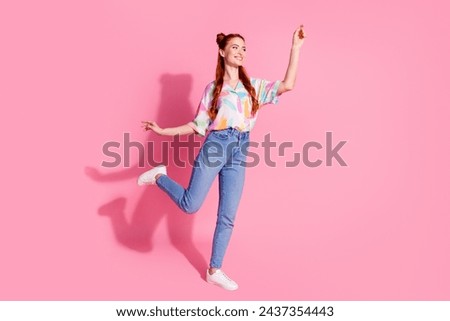 Full size photo of lovely girl dressed colorful blouse jeans pants catching product look empty space isolated on pink color background