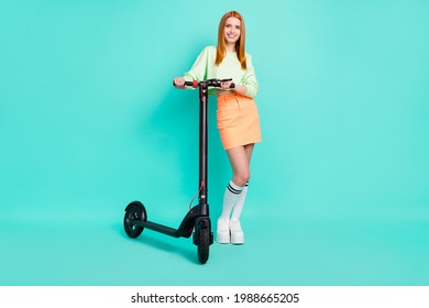 Full size photo of lovely millennial lady stand scooter wear sport clothes isolated on vivid teal color background
