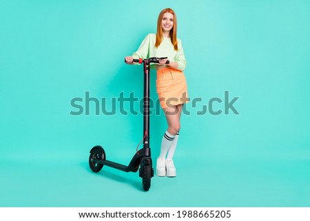 Full size photo of lovely millennial lady stand scooter wear sport clothes isolated on vivid teal color background