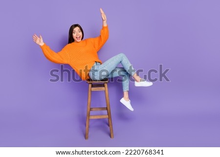 Full size photo of lovely young woman sit stool falling lean over dressed stylish orange knitted outfit isolated on purple color background