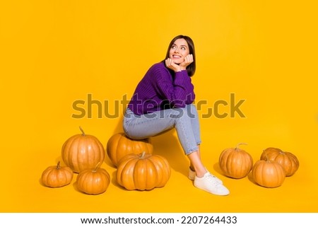 Full size photo of minded adorable person sitting pumpkin look empty space isolated on yellow color background