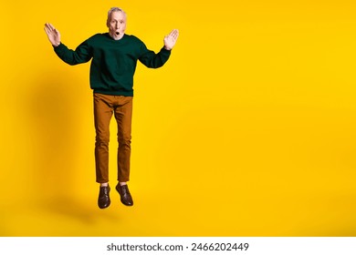 Full size photo of nice senior man jump falling down dressed stylish green clothes isolated on yellow color background - Powered by Shutterstock