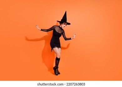 Full Size Photo Of Nice Woman Bend Over Peek Curious Empty Space Dressed Trendy Black Halloween Outfit Isolated On Orange Color Background