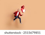 Full size photo of nice young man jump balloon show v-sign wear red shirt isolated on beige color background