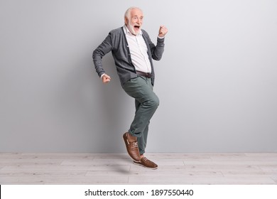Full size photo of old optimistic man dance wear dark sweater trousers boots isolated on grey wall