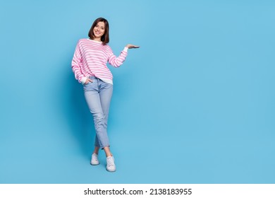 Full size photo optimistic millennial lady stand hold promo wear shirt jeans shoes isolated blue background