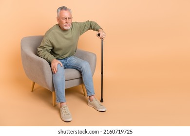 Full size photo of optimistic old grey sad man sit with stick wear pullover jeans shoes isolated on beige background - Powered by Shutterstock